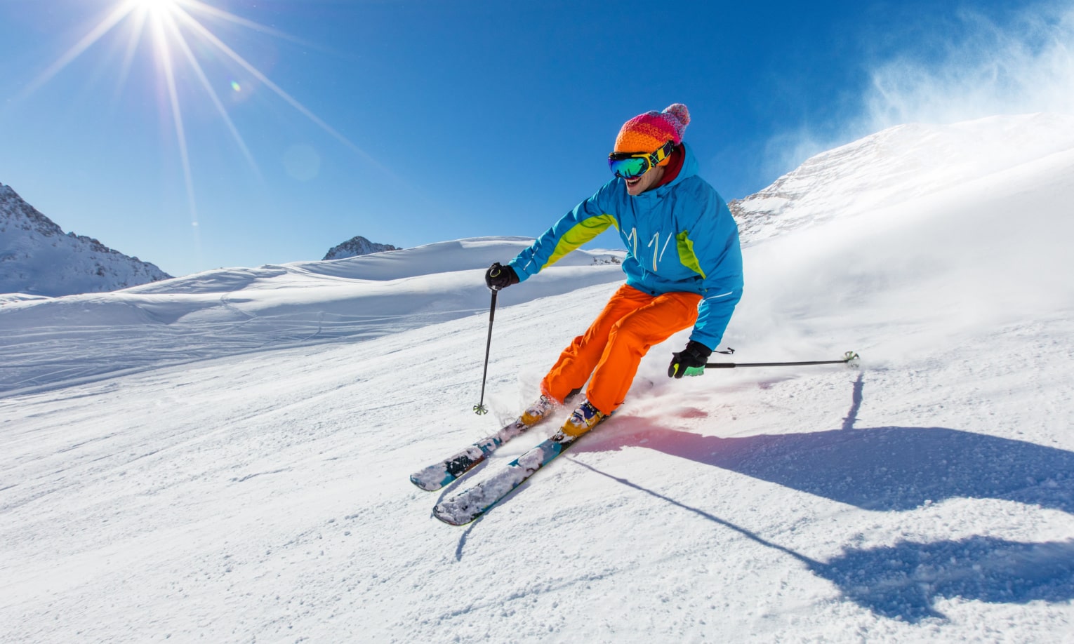 мужчина в яркой лыжной одежде катается на лыжах в горах