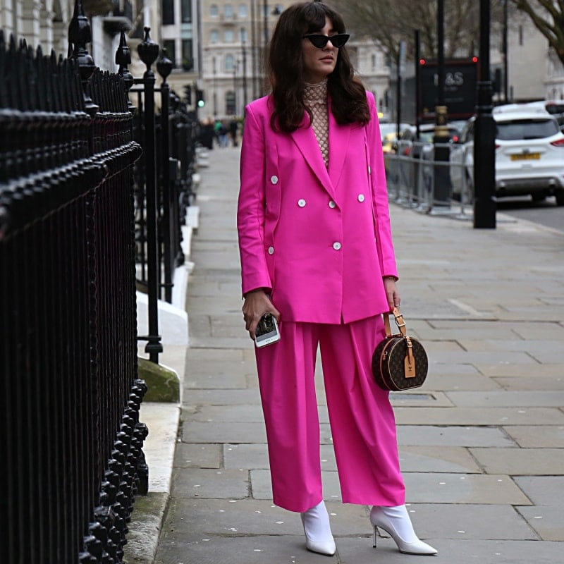 женщина в розовом костюме стоит на улице