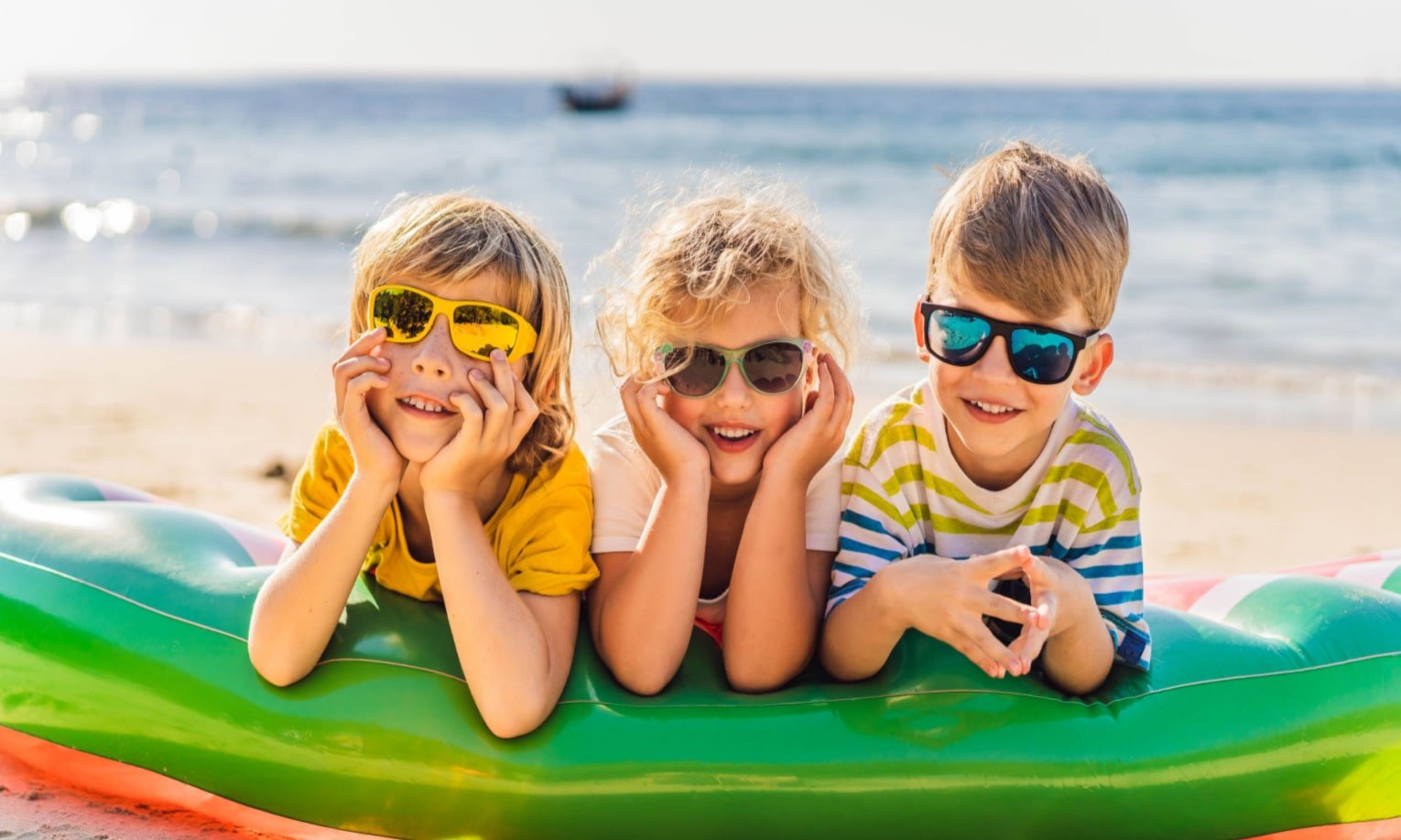 vaikai su saules akiniais prie juros