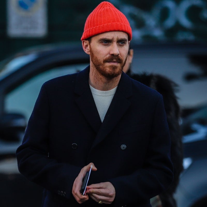 mees punase mütsi ja musta mantliga tänaval