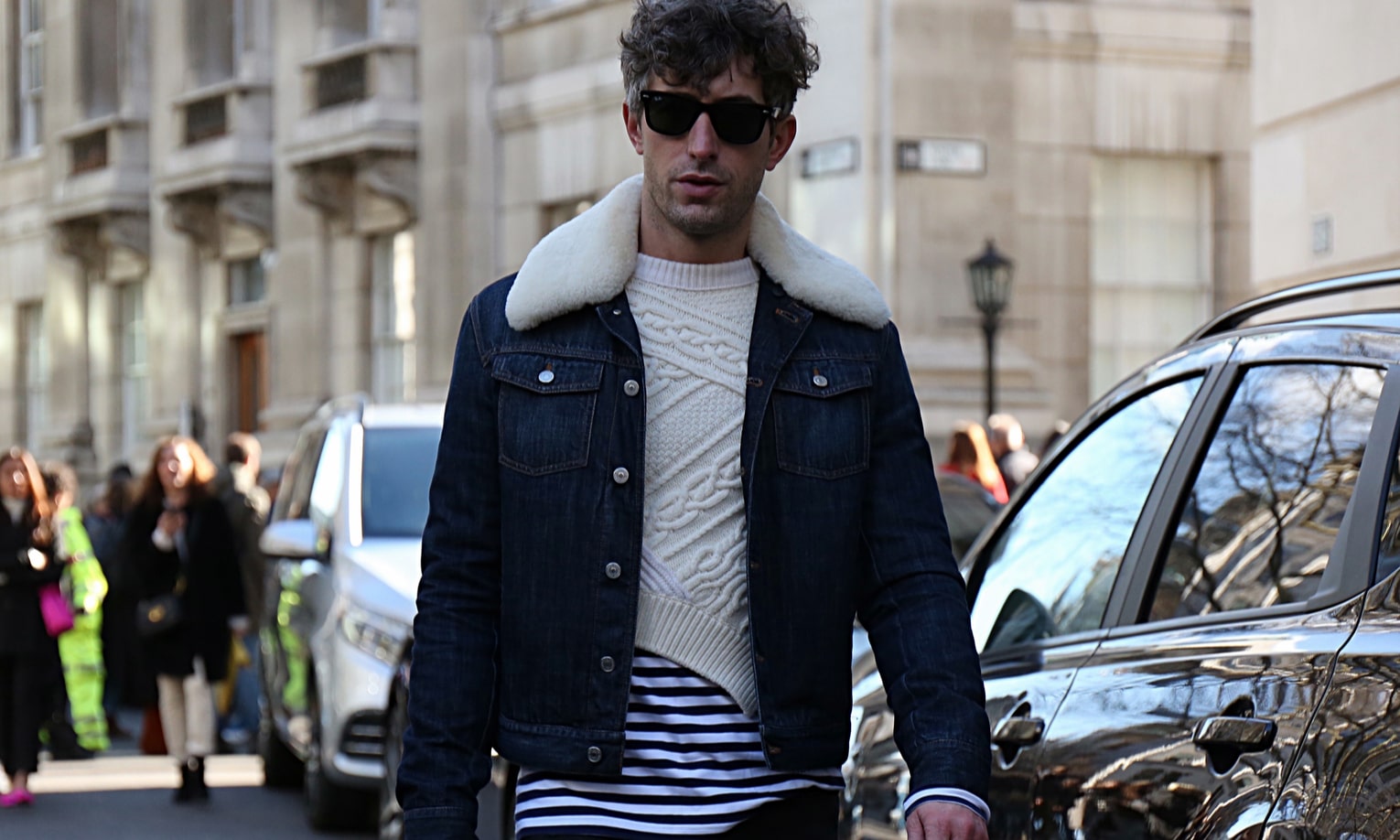 мужчина в джинсовой куртке гуляет по городу