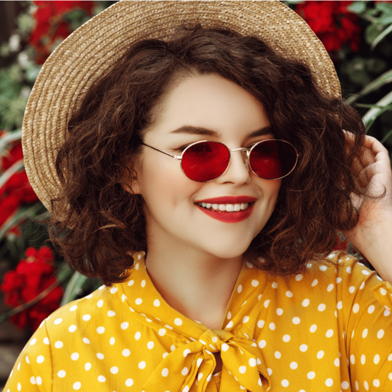 punaste ovaalsete prillide ja mütsiga tüdruk naeratab