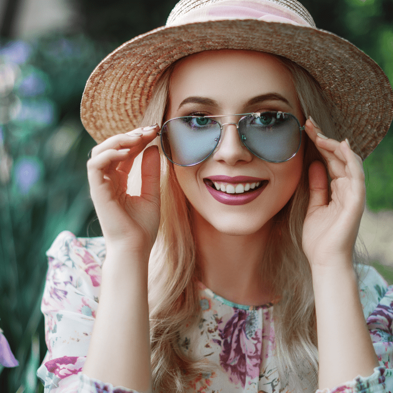blondine mergina su skrybele ir aviatoriaus akiniais nuo saules sypsosi gamtoje