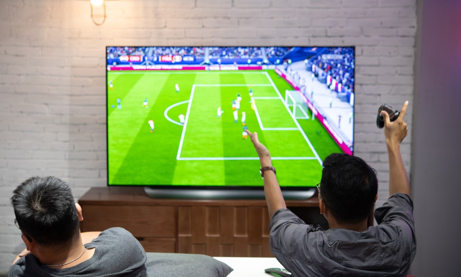 два парня смотрят футбольный матч по телевизору