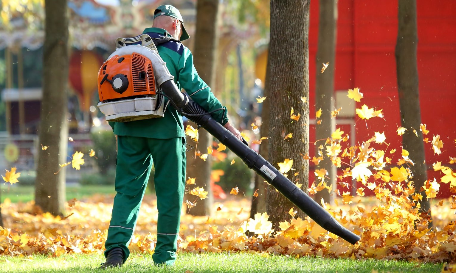 мужчина убирает опавшие листья с помощью воздуходувки-рюкзака