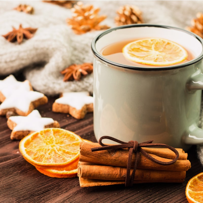 чашка чая с долькой апельсина и палочкой корицы