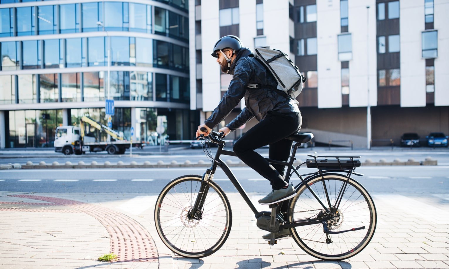 мужчина едет на электрическом велосипеде по городу