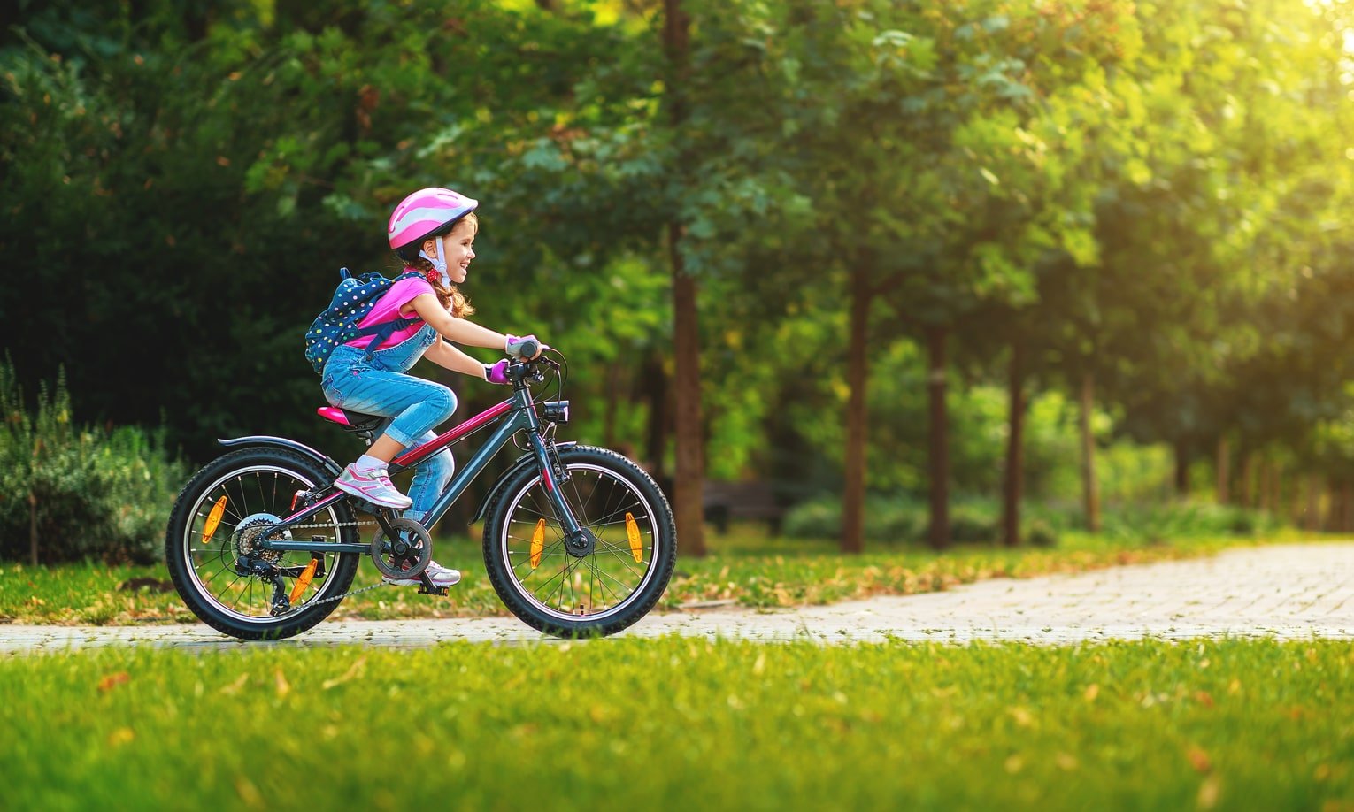 tüdruk sõidab rõõmsalt pargis jalgrattaga