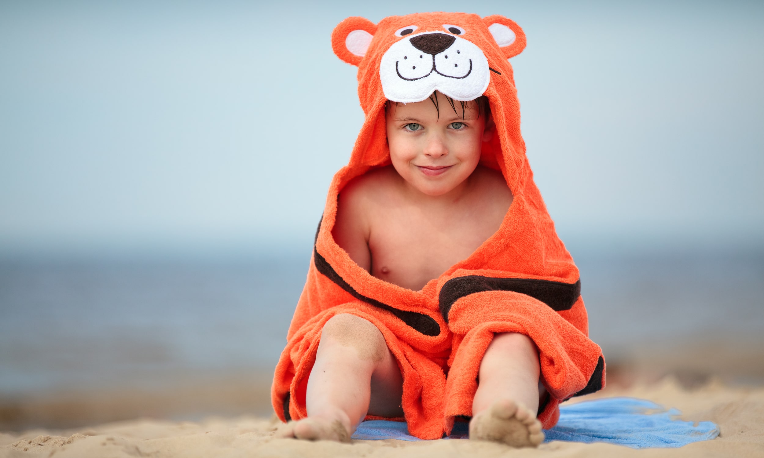 Мальчик у моря с тигровым полотенцем