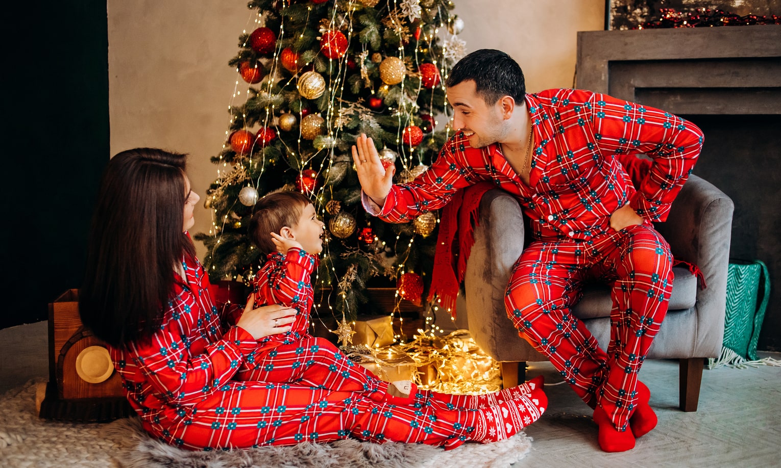 семья в рождественских пижамах возле елки
