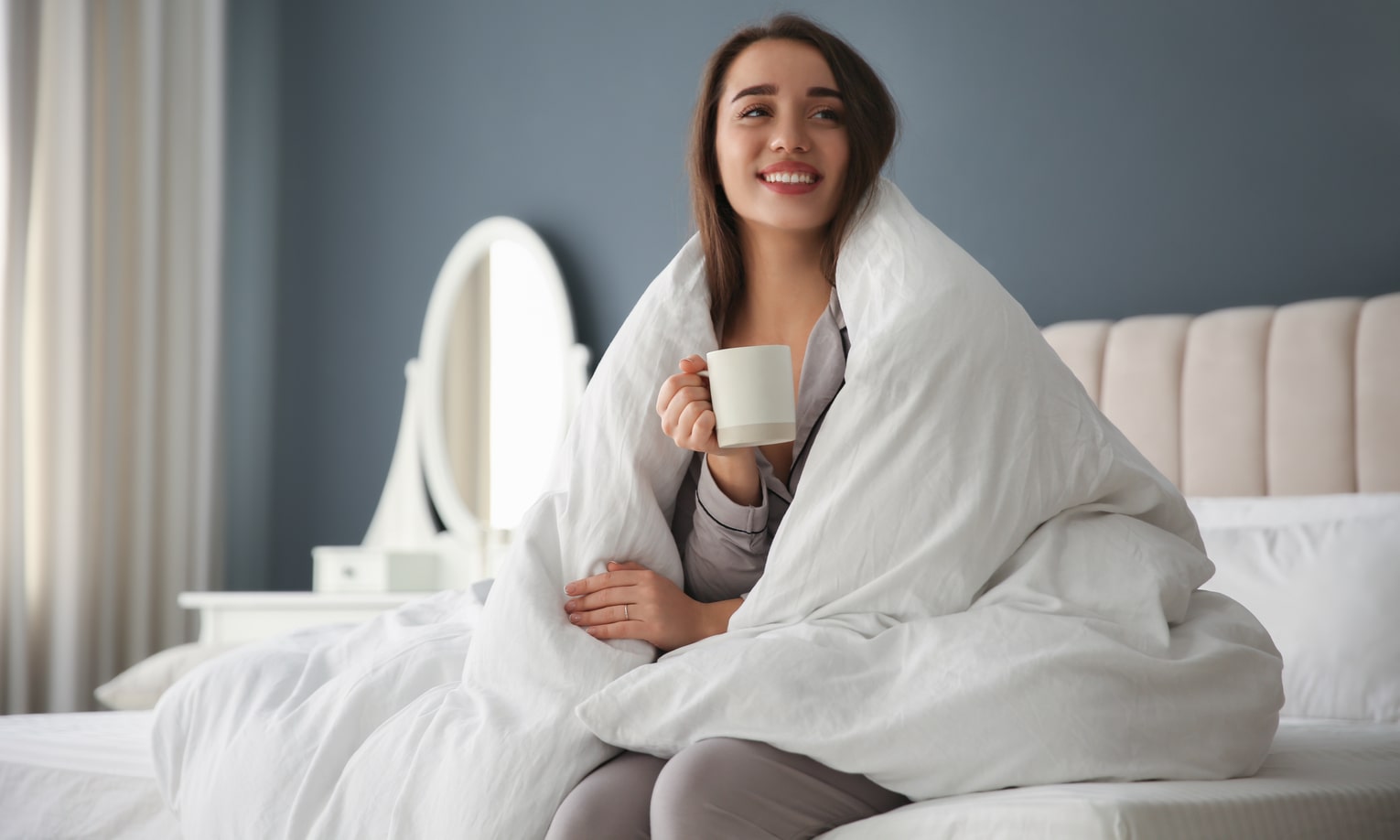 девушка завернувшись в теплое одеяло пьет кофе