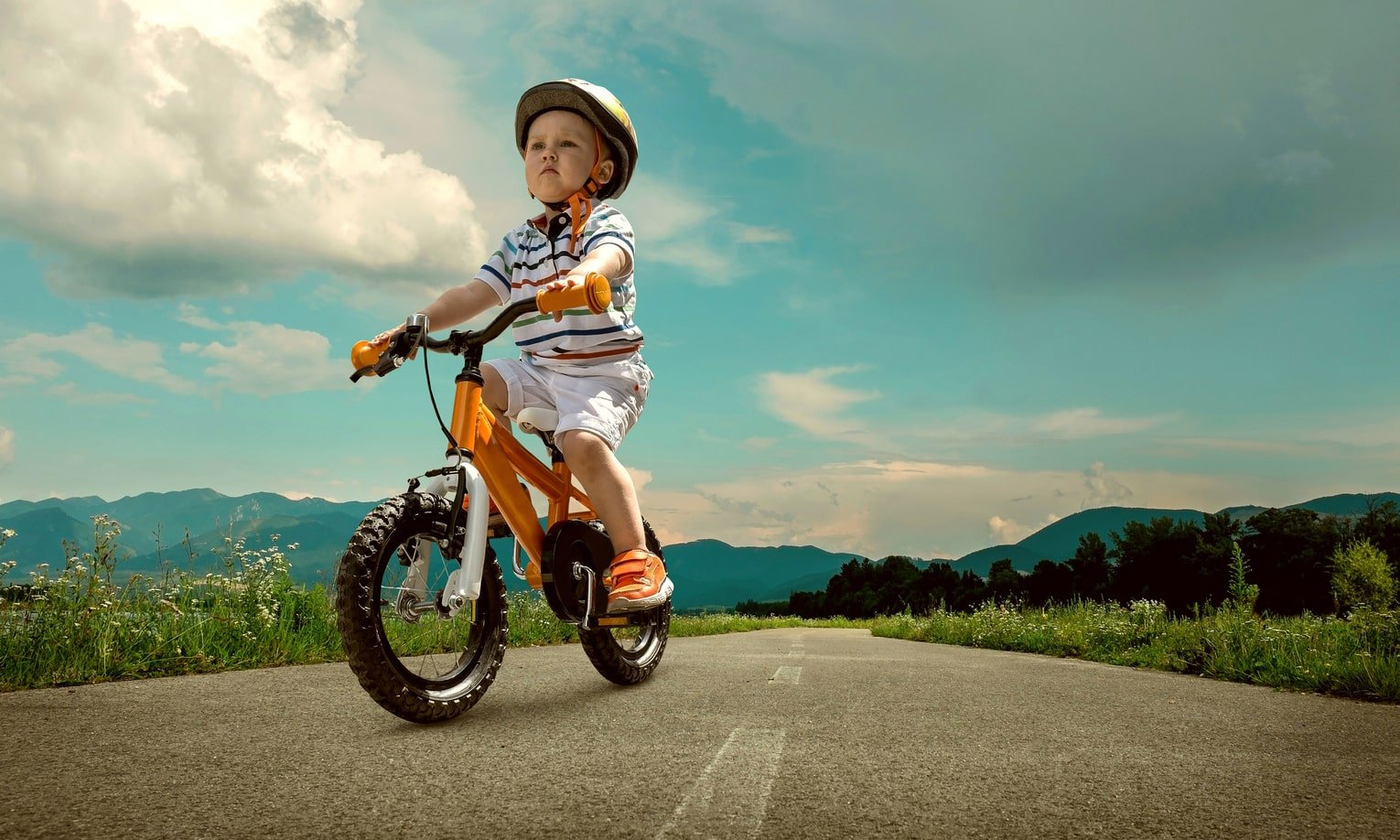 väike poiss sõidab jalgrattaga maanteel