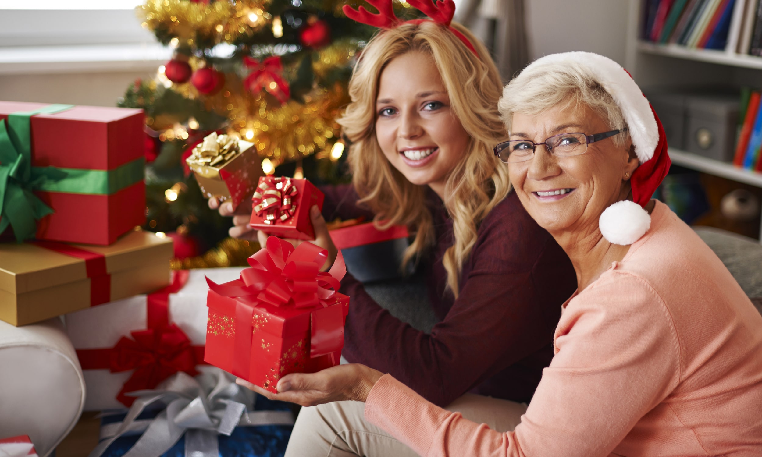 бабушка и внучка дарят друг другу подарки у елки
