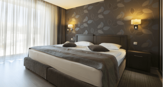 romantiskas miegamojo kambarys su gelsvais sieniniais sviestuvais ir baltomis uzuolaidomis