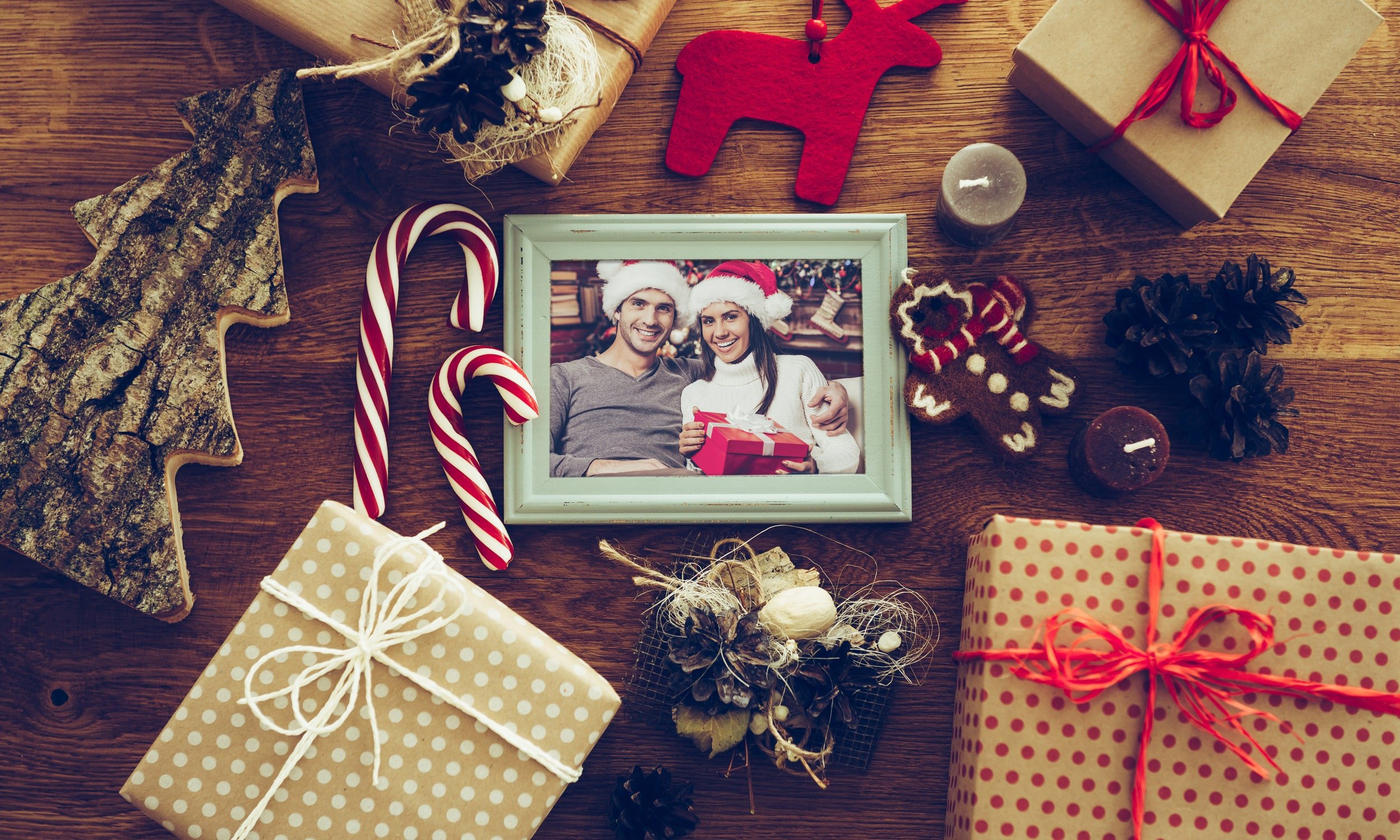 рождественские подарки и фото пары в рамке на столе