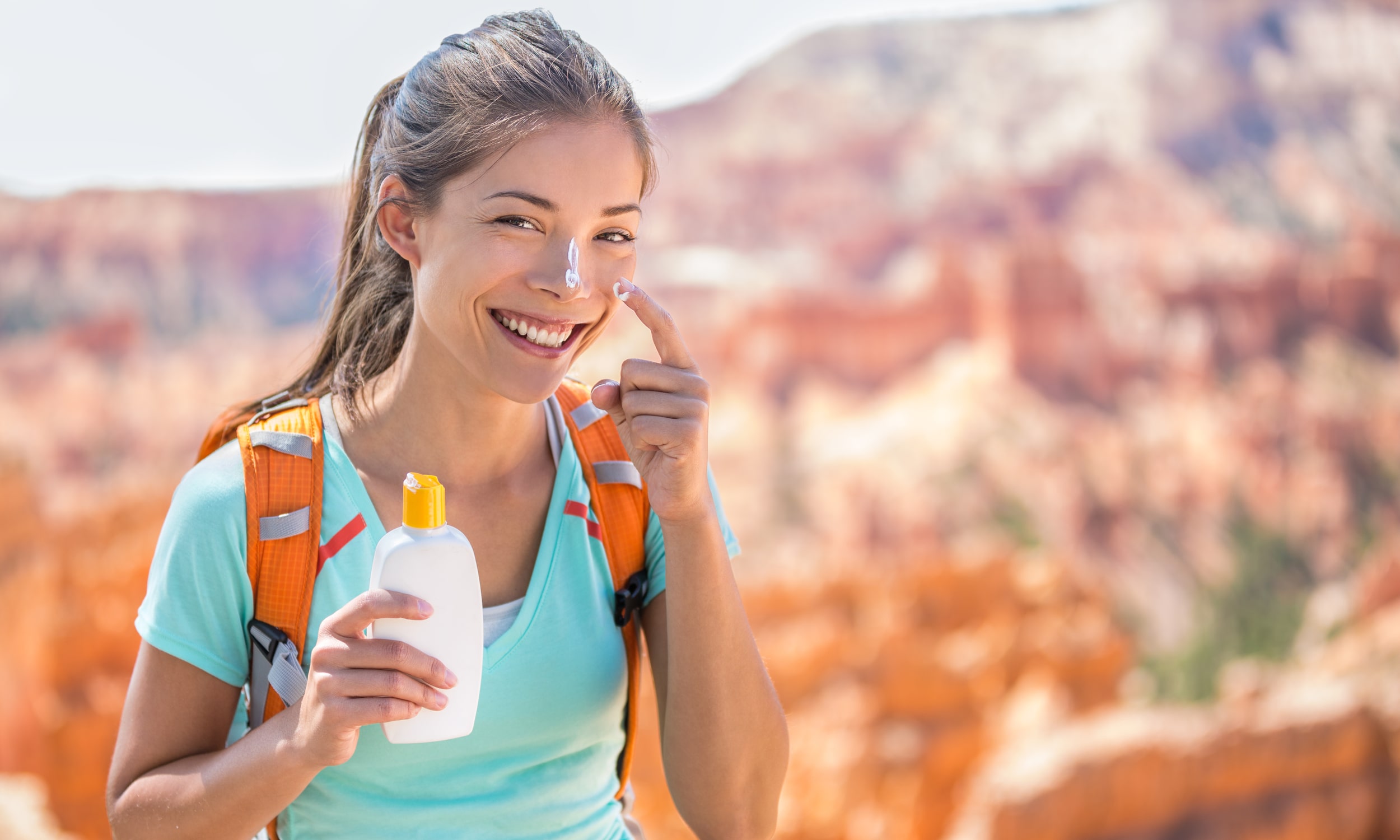девушка пользуется кремом для лица с солнцезащитным фактором spf во время активных занятий на природе