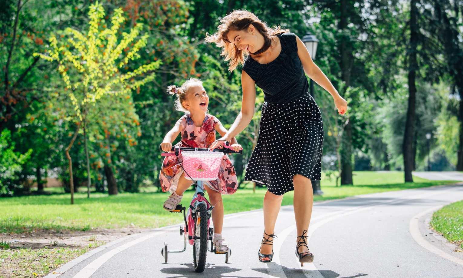 мать учит дочку кататься на велосипеде
