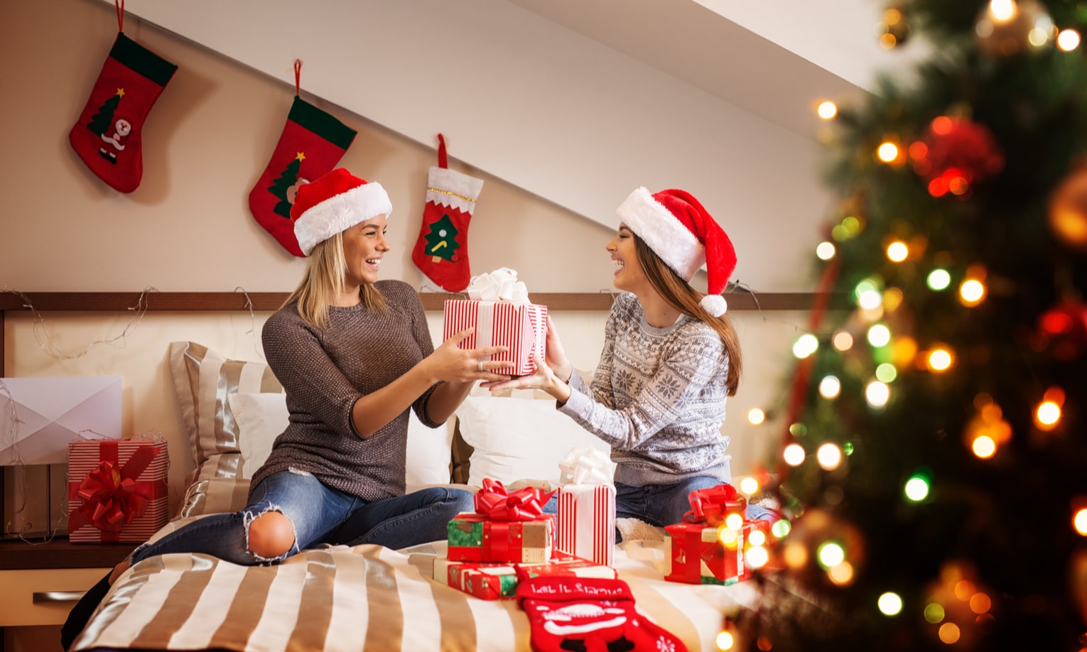 сестры дарят друг другу рождественские подарки у елки