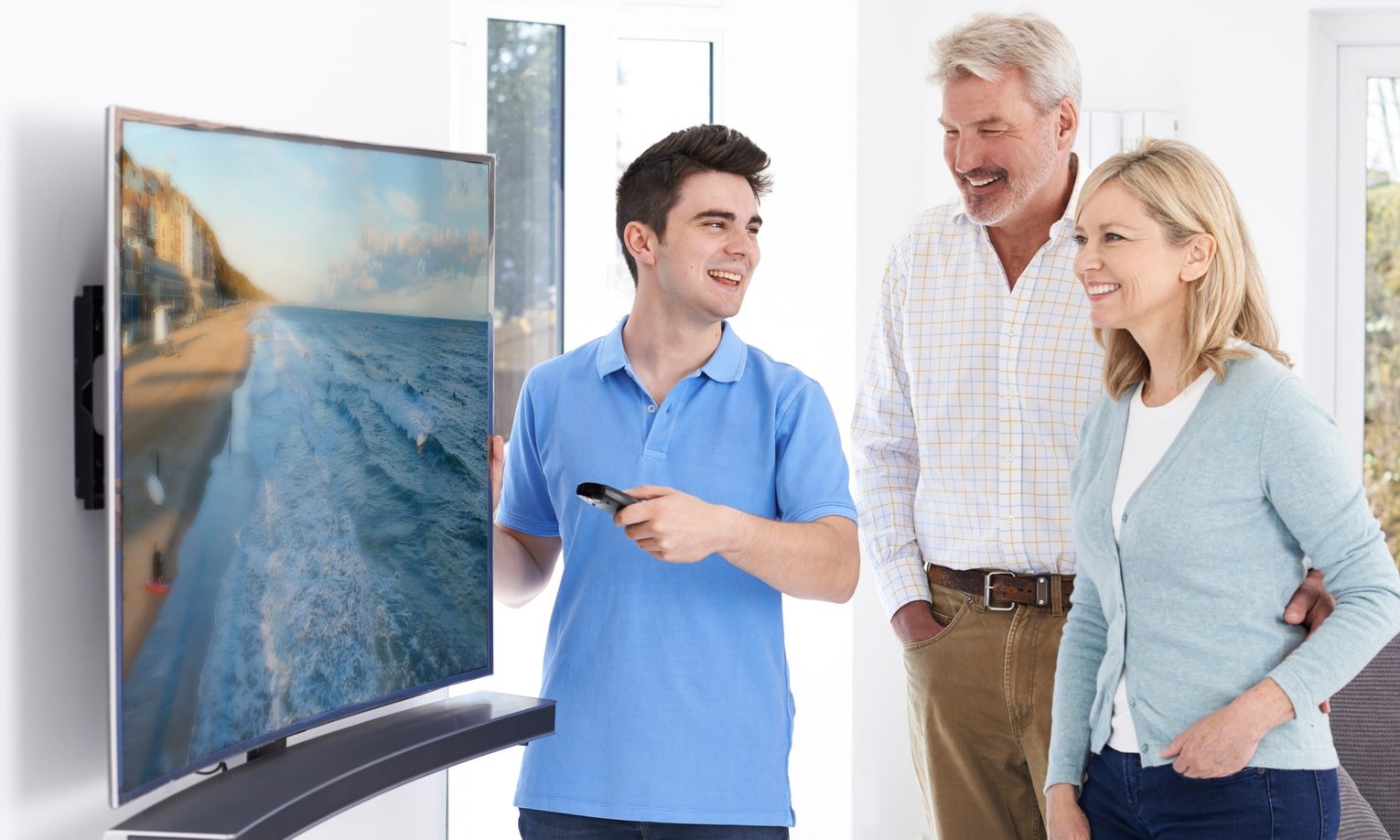парень показывает телевизор с изогнутым экраном покупателям