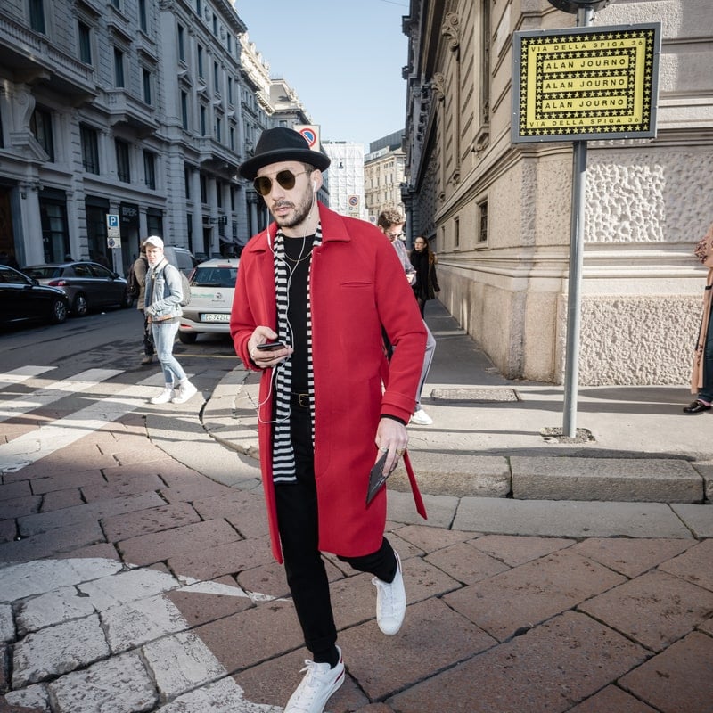 мужчина в красном пальто гуляет по городу