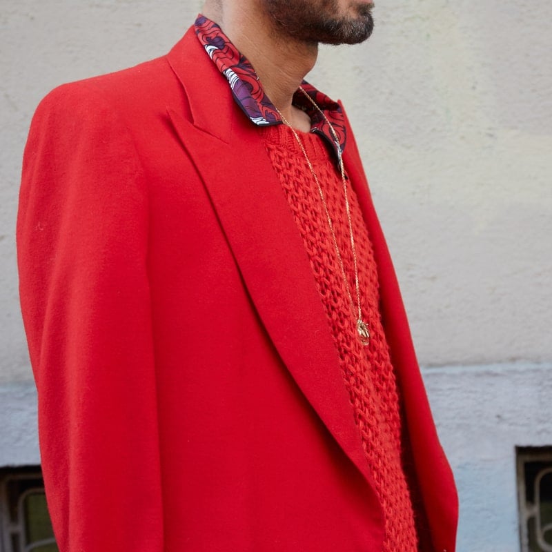мужчина в красном пиджаке гуляет по городу