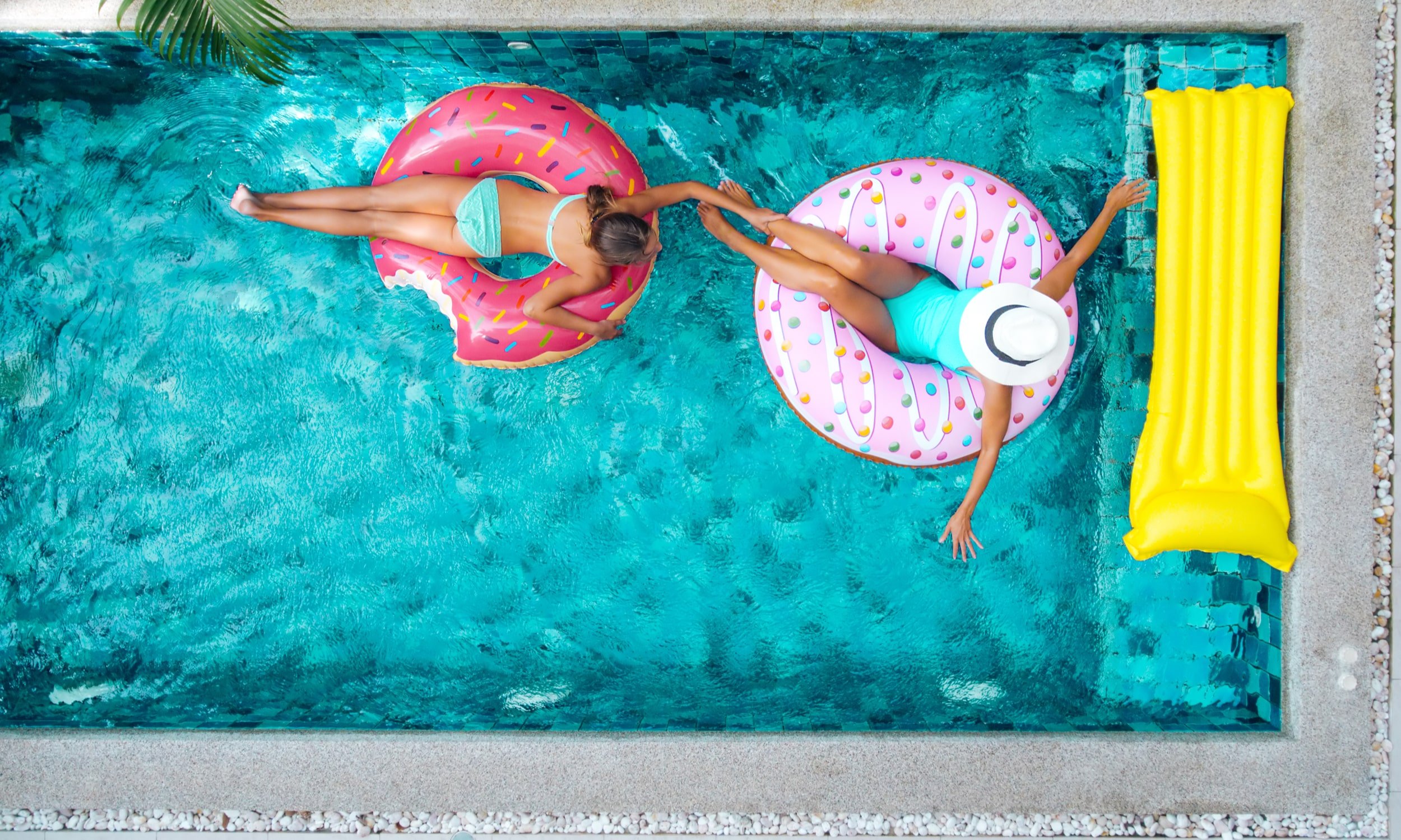 девушки плавают в бассейне с надувными кругами
