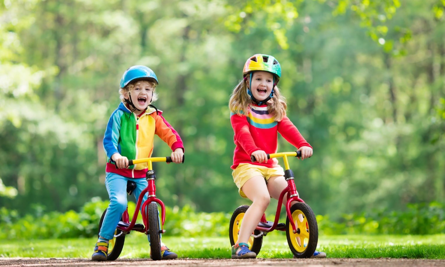 vaikai vazineja su balansiniais dviraciais parke