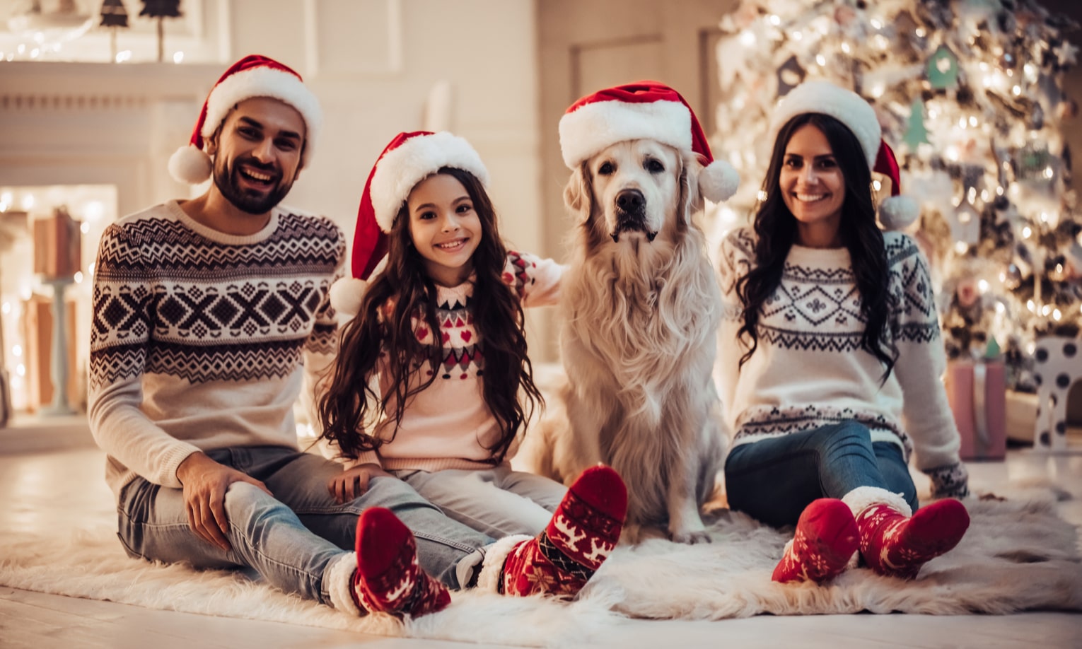 семья в рождественских свитерах и шапках деда мороза